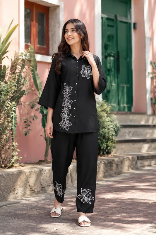 Rabric black rayon co-ord set lifestyle image with white embroidered flower print, short shirt and matching pant for women
