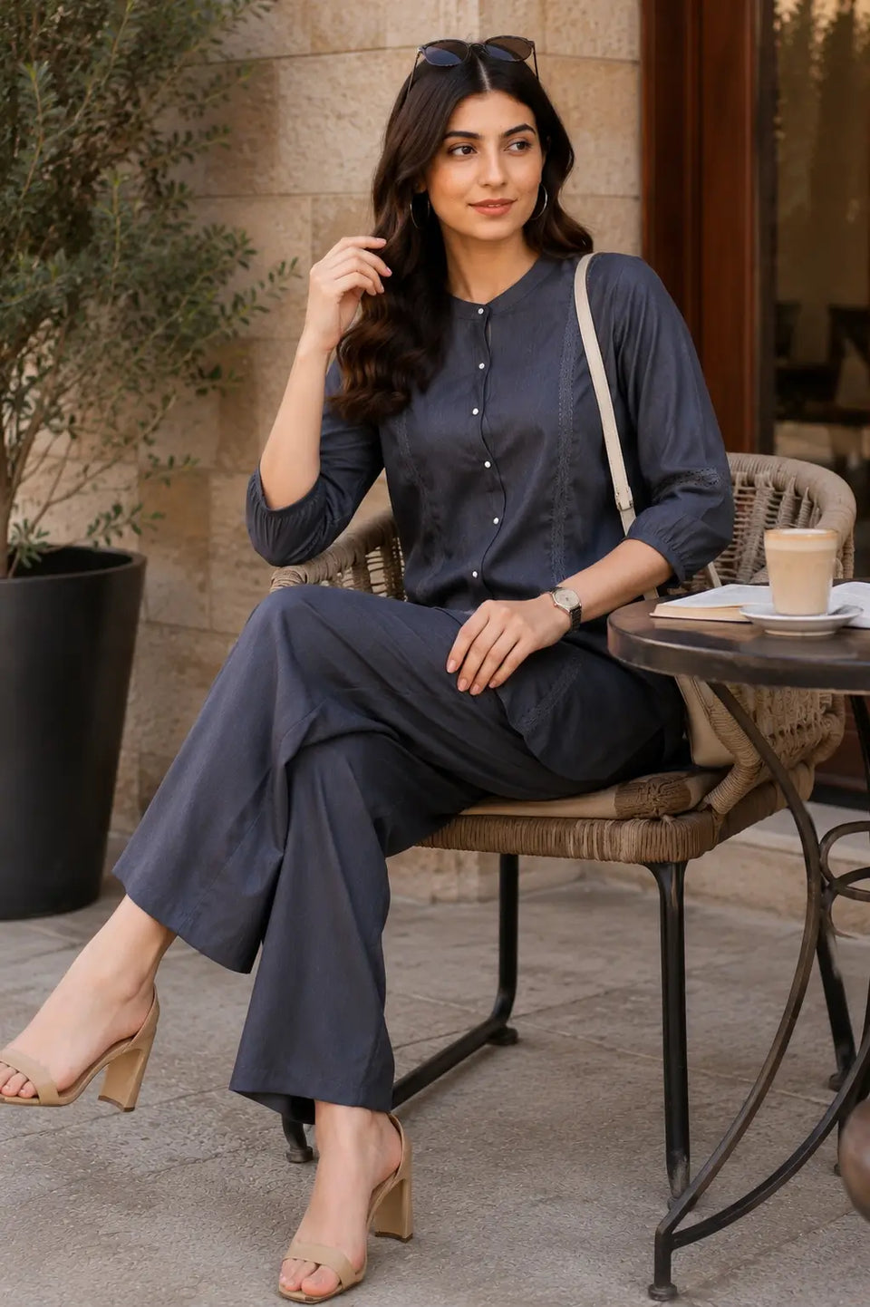 Rabric charcoal grey Vertican Silk co-ord set in a chic cafe lifestyle setting featuring lace panels, round neck and comfortable straight pants.