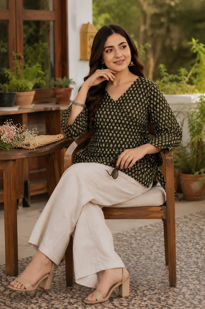 Rabric olive green Cotton floral short top in casual sitting pose with cream palazzo, bell sleeves and elegant everyday styling.