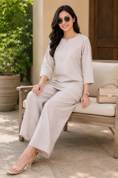 Rabric beige solid cotton co-ord set for women in casual sitting pose with sunglasses, handbag, notch neck top and wide palazzo pants