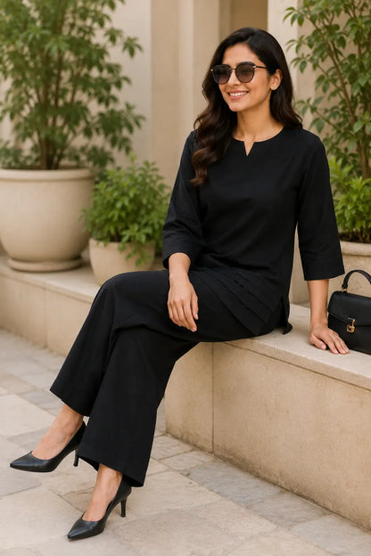 Rabric black cotton co-ord set in sitting pose for women with solid plain cotton fabric, notch neck top and comfortable wide-leg palazzo pants