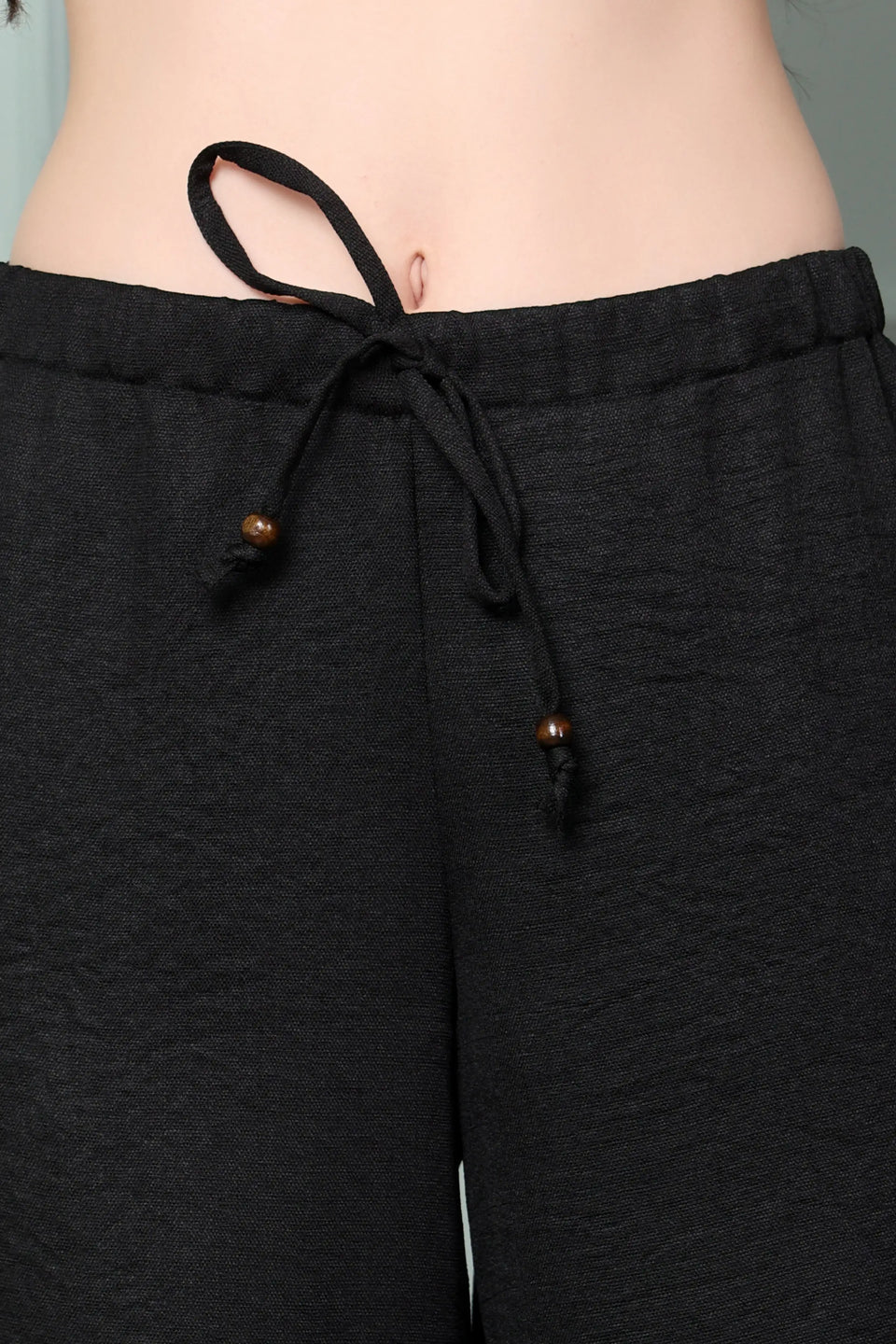 RABRIC black linen women trousers close-up with elastic waist, two pockets and wooden ring drawstring