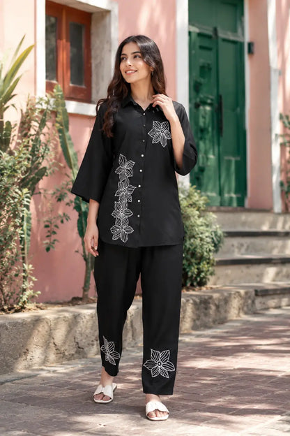 Rabric black rayon co-ord set lifestyle image with white embroidered flower print, short shirt and matching pant for women