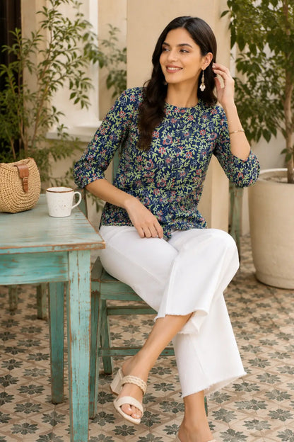 Woman sitting casually wearing Rabric blue floral cotton short top with elegant summer accessories