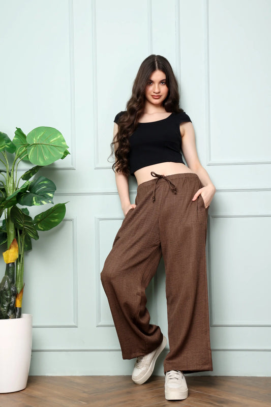Woman standing in RABRIC chocolate brown linen wide leg trousers showing full length and broad fit