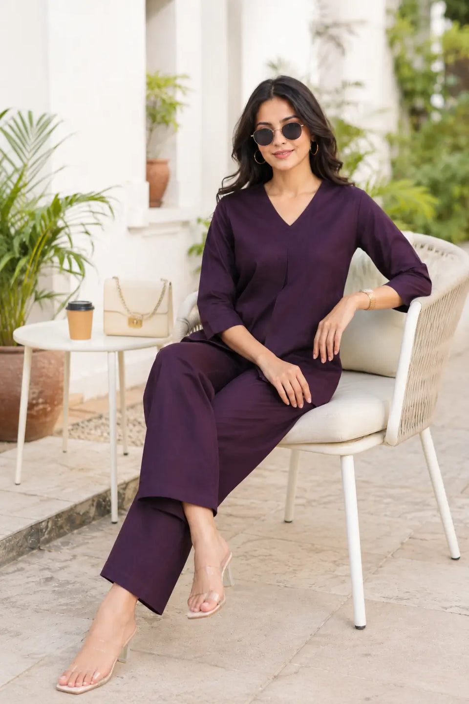 Rabric dark plum solid plain cotton co-ord set for women in casual sitting pose with accessories, V-neck top and wide pajama
