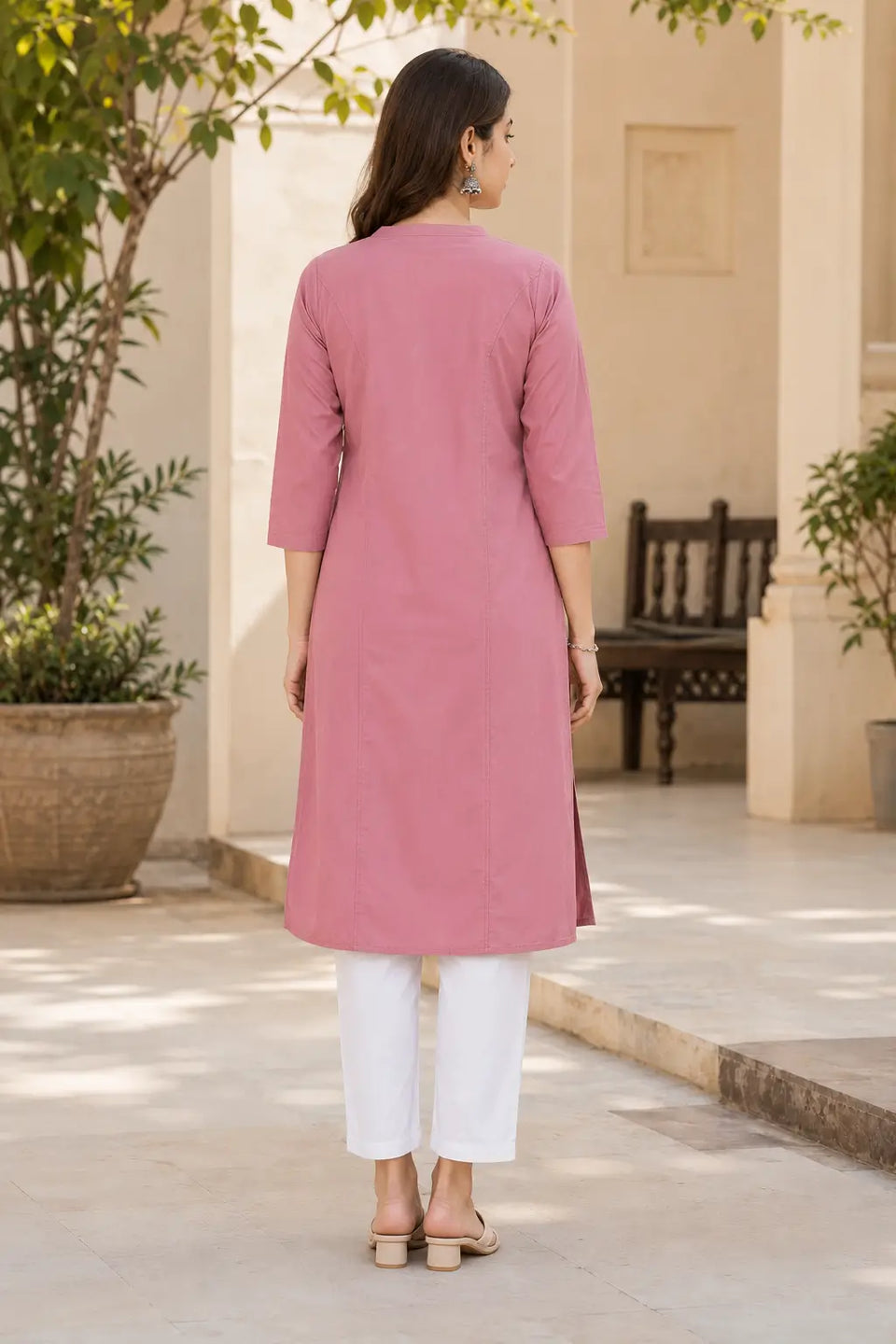 Back view of Rabric dusty rose pink rayon solid long straight kurti for women with clean seam detailing, 3/4 sleeves and white pants