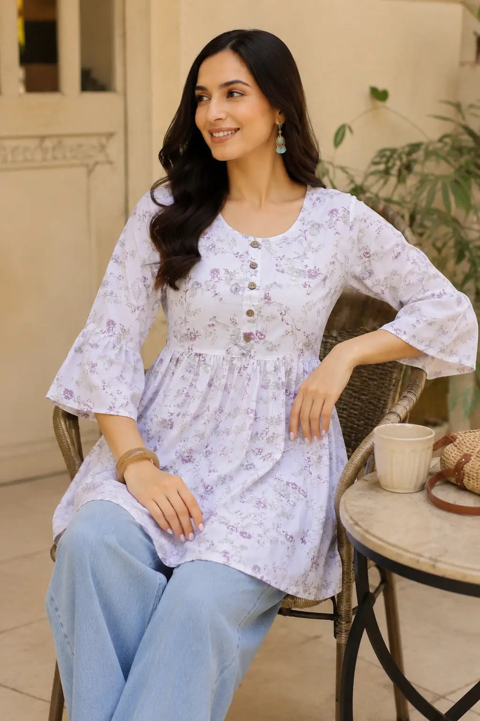 Lifestyle sitting pose of model wearing Rabric floral cotton short top with relaxed chic styling