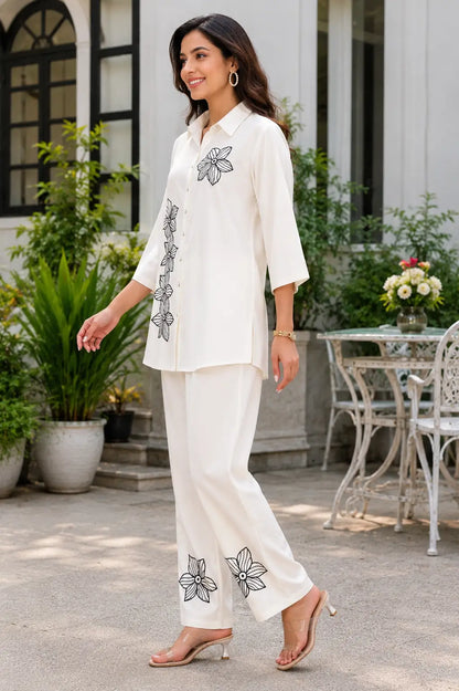 Side angle view of Rabric ivory rayon women’s co-ord set with black floral embroidered short shirt and matching straight pants