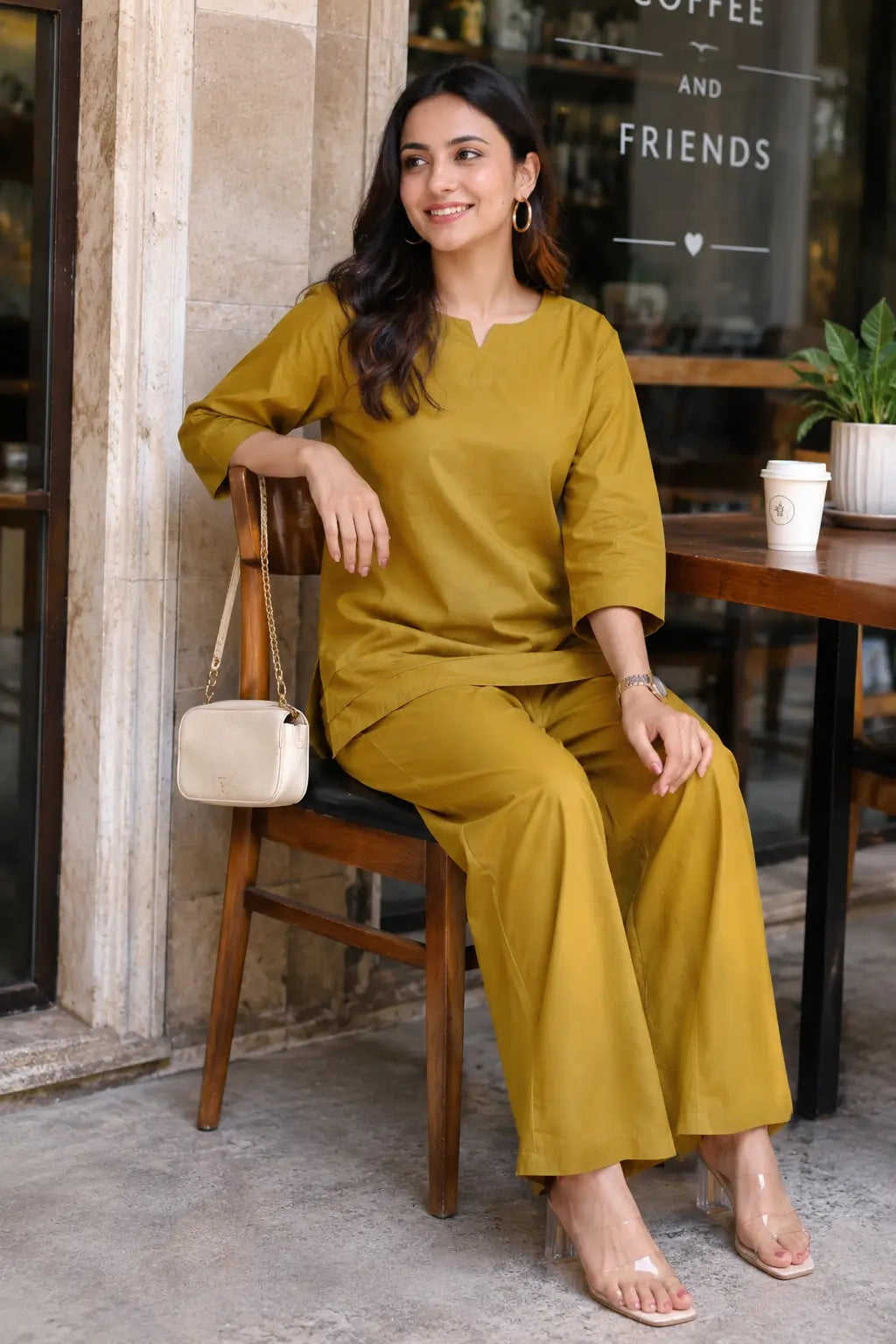 Rabric mustard olive cotton co-ord set for women in cafe sitting pose with notch neck top and matching wide leg pants