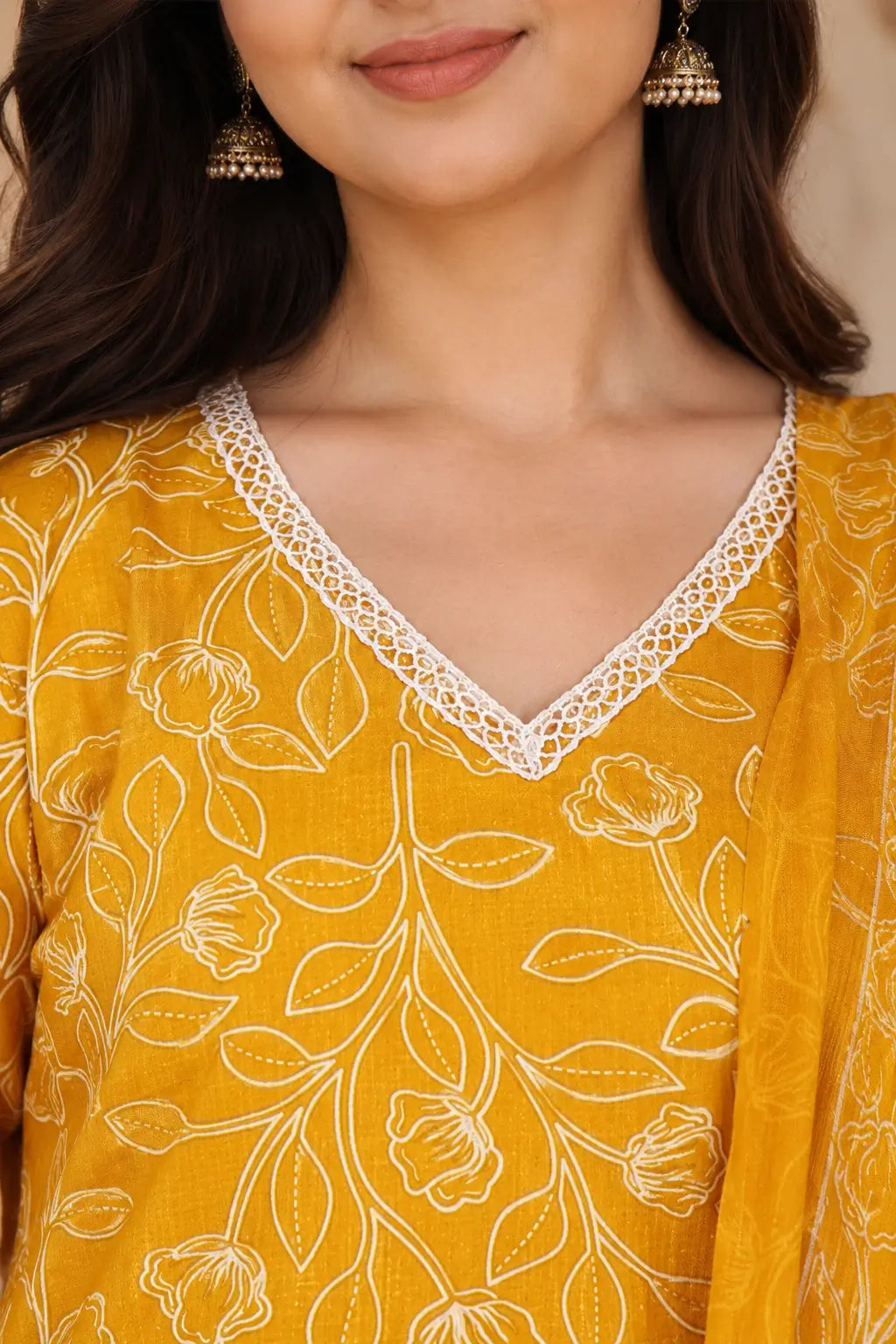 Closeup of V neck lace design on Rabric mustard yellow cotton floral printed kurta with delicate white lace border detailing.