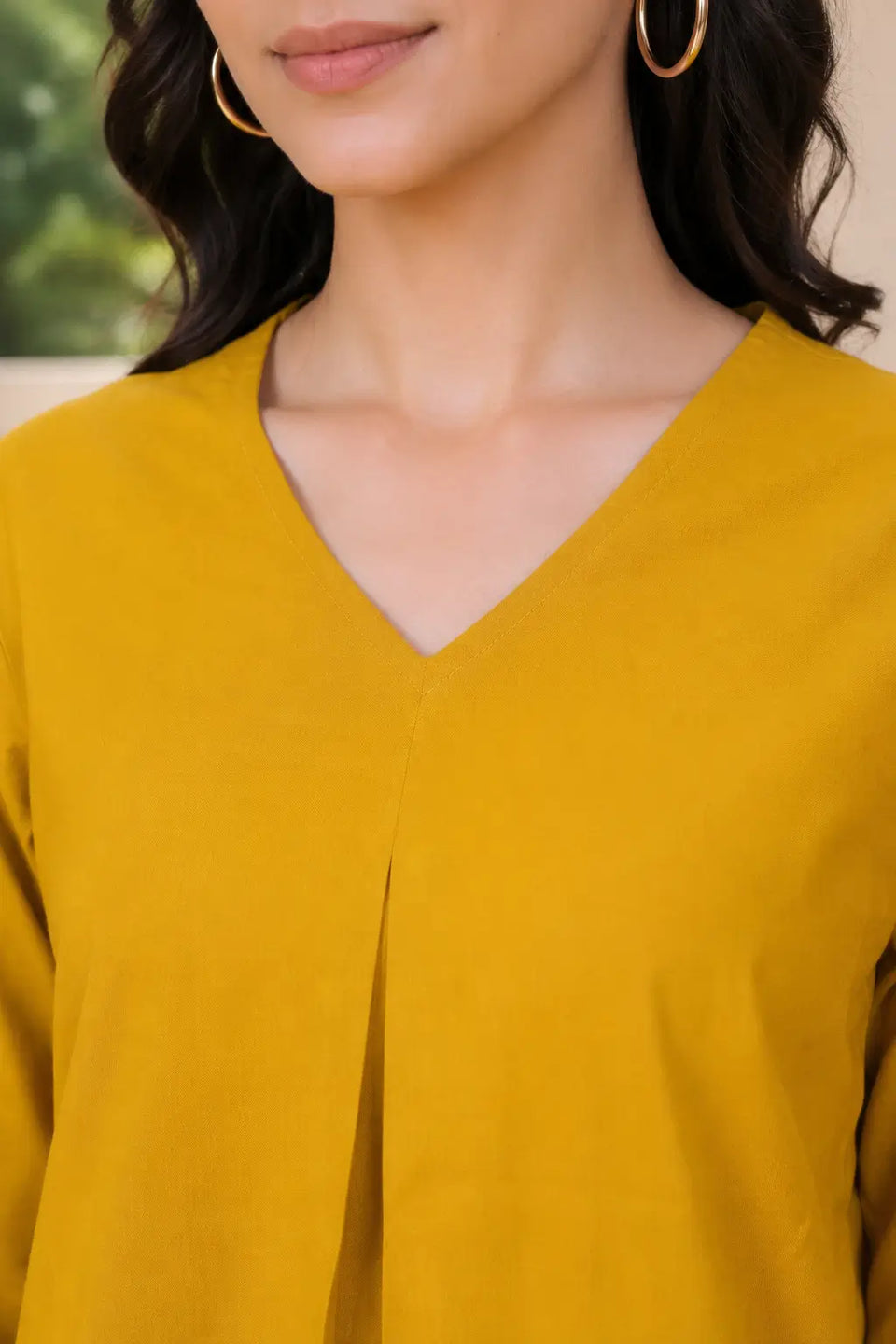 Close-up of Rabric mustard yellow solid cotton co-ord set showing the V-neck stitching and centre pleat on the plain short top.