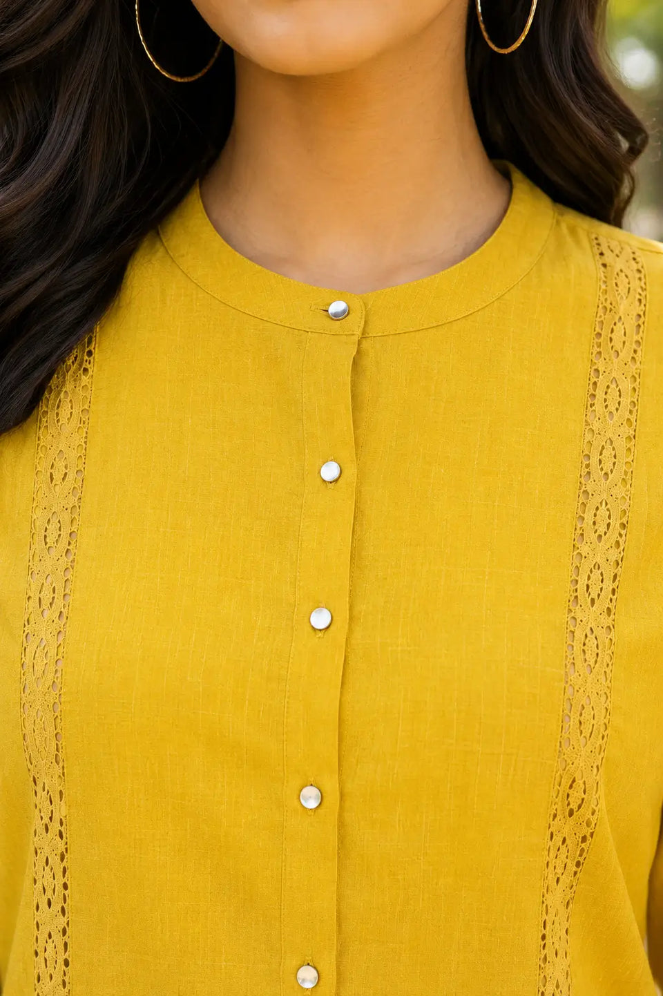 Close-up of round neck and pearl button detailing on Rabric mustard yellow Vertican Silk co-ord set featuring premium textured fabric and elegant finish.