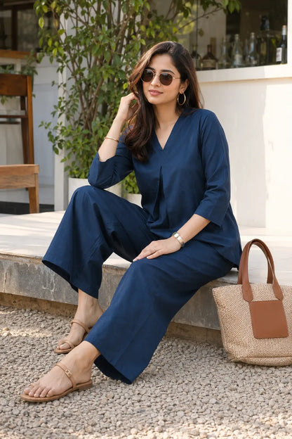 Rabric navy blue cotton co-ord set for women in casual sitting pose with accessories, solid V-neck top and wide-leg pajama