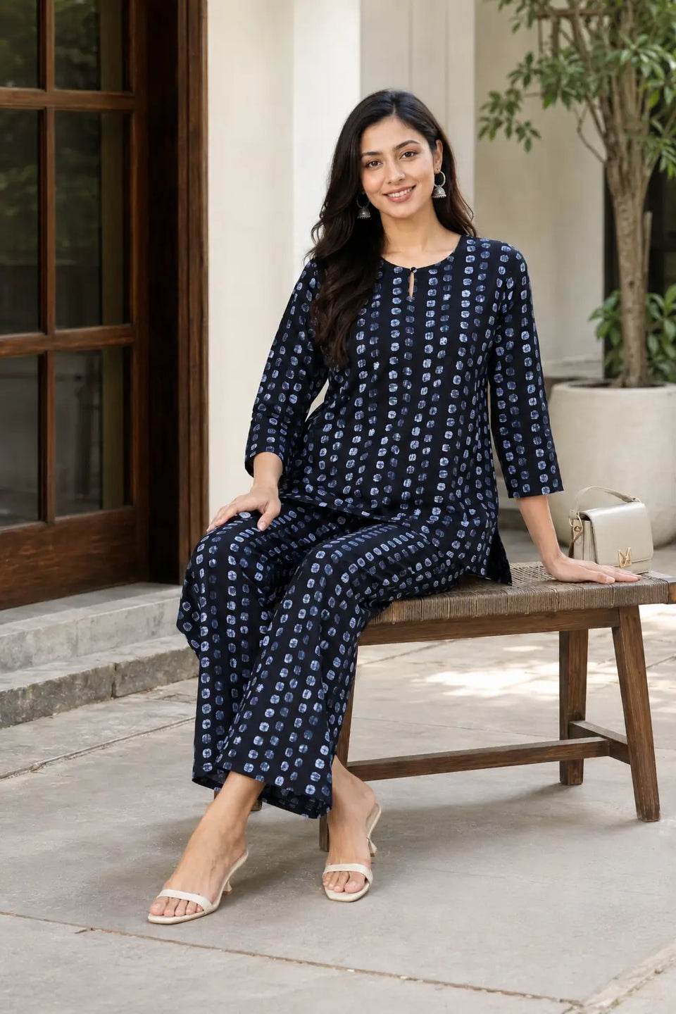 Woman in Rabric navy blue cotton co-ord set with light blue abstract dotted print, short top and wide-leg pajama in relaxed sitting lifestyle pose