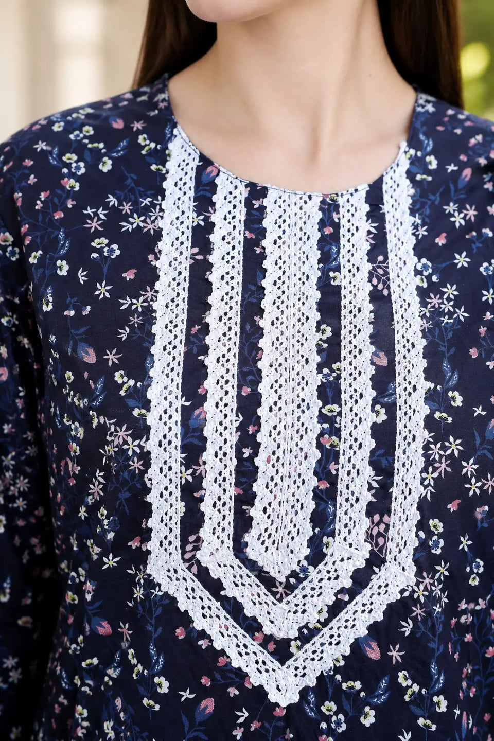 Close-up of Rabric navy blue cotton floral printed kurti showing detailed V-neck white embroidered lace design and small multicolor floral print.