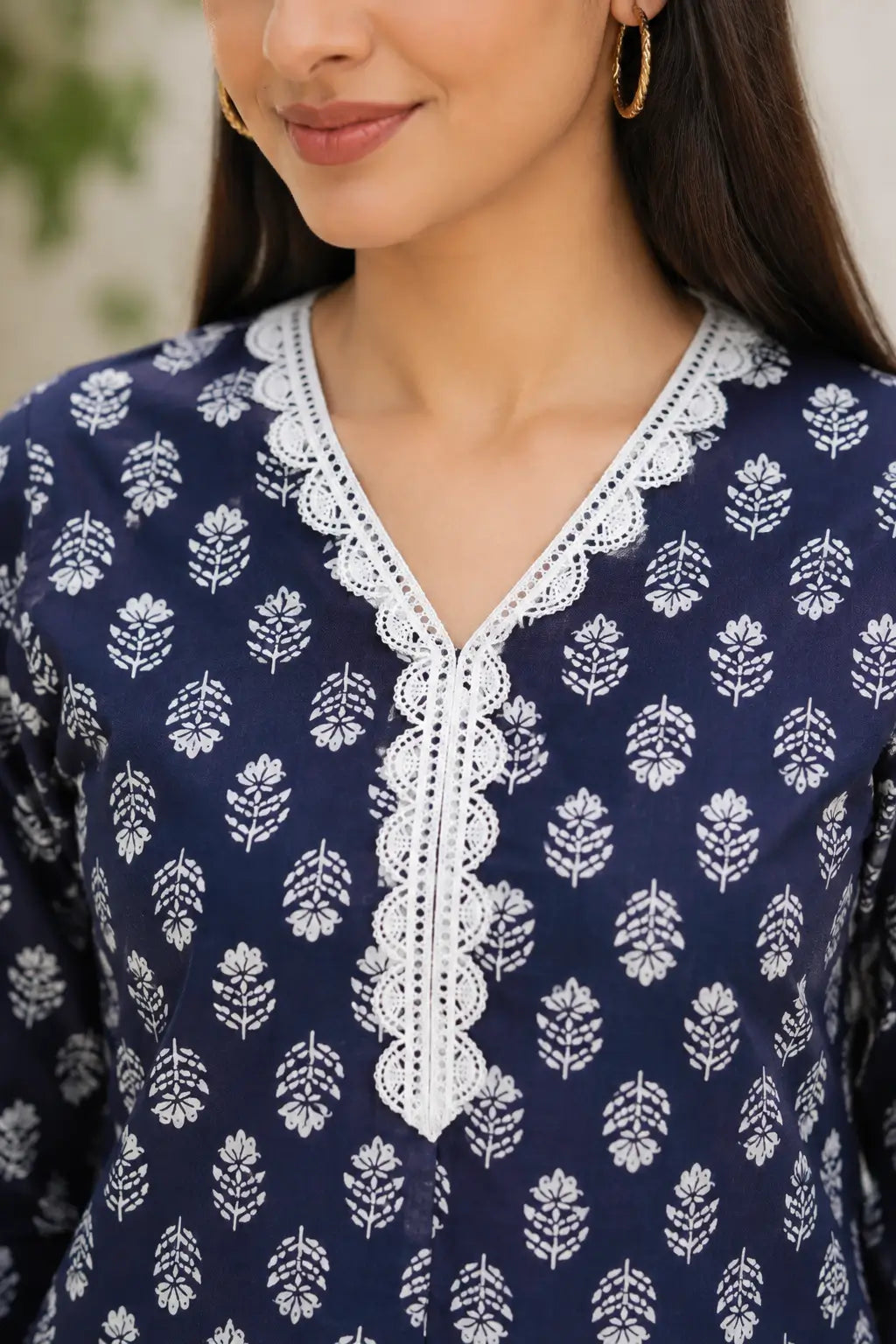 Close-up of Rabric navy blue cotton kurti with white leaf floral print and beautiful white embroidered lace V-neck design