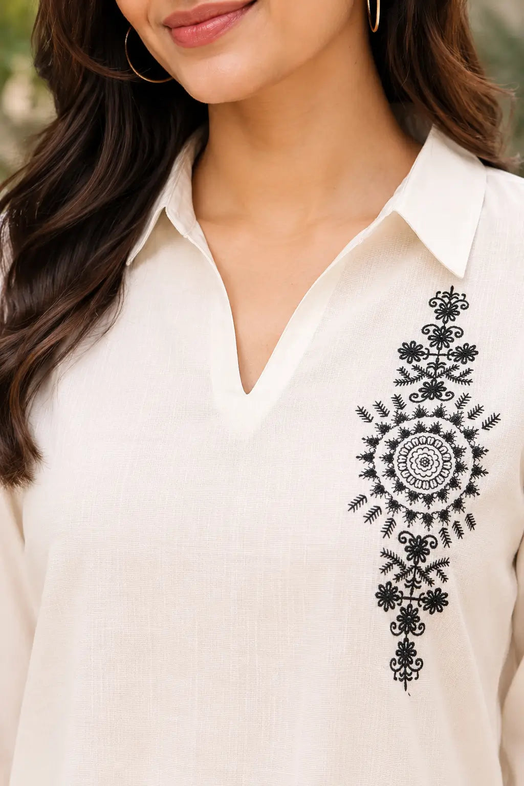 Close up of Rabric off white cotton co-ord set showing collar V neck design, textured cotton fabric and black floral embroidery