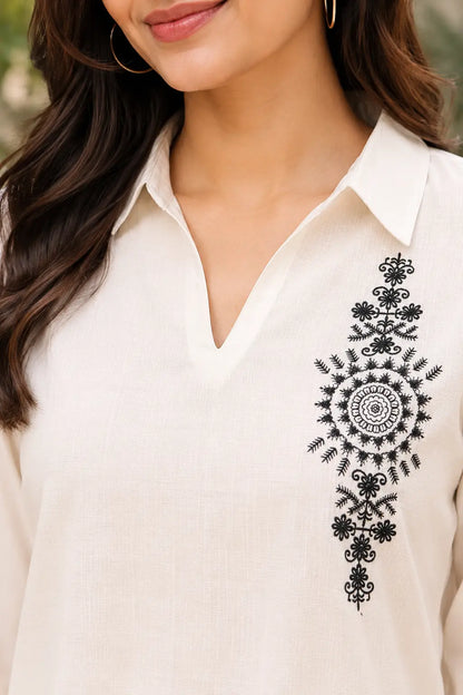 Close up of Rabric off white cotton co-ord set showing collar V neck design, textured cotton fabric and black floral embroidery