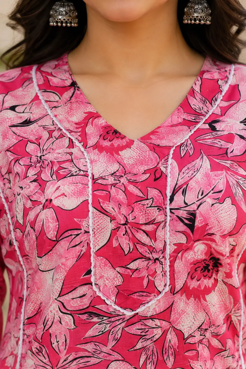 Closeup of stylish V neck design on Rabric pink floral cotton kurti for women with detailed ethnic piping work