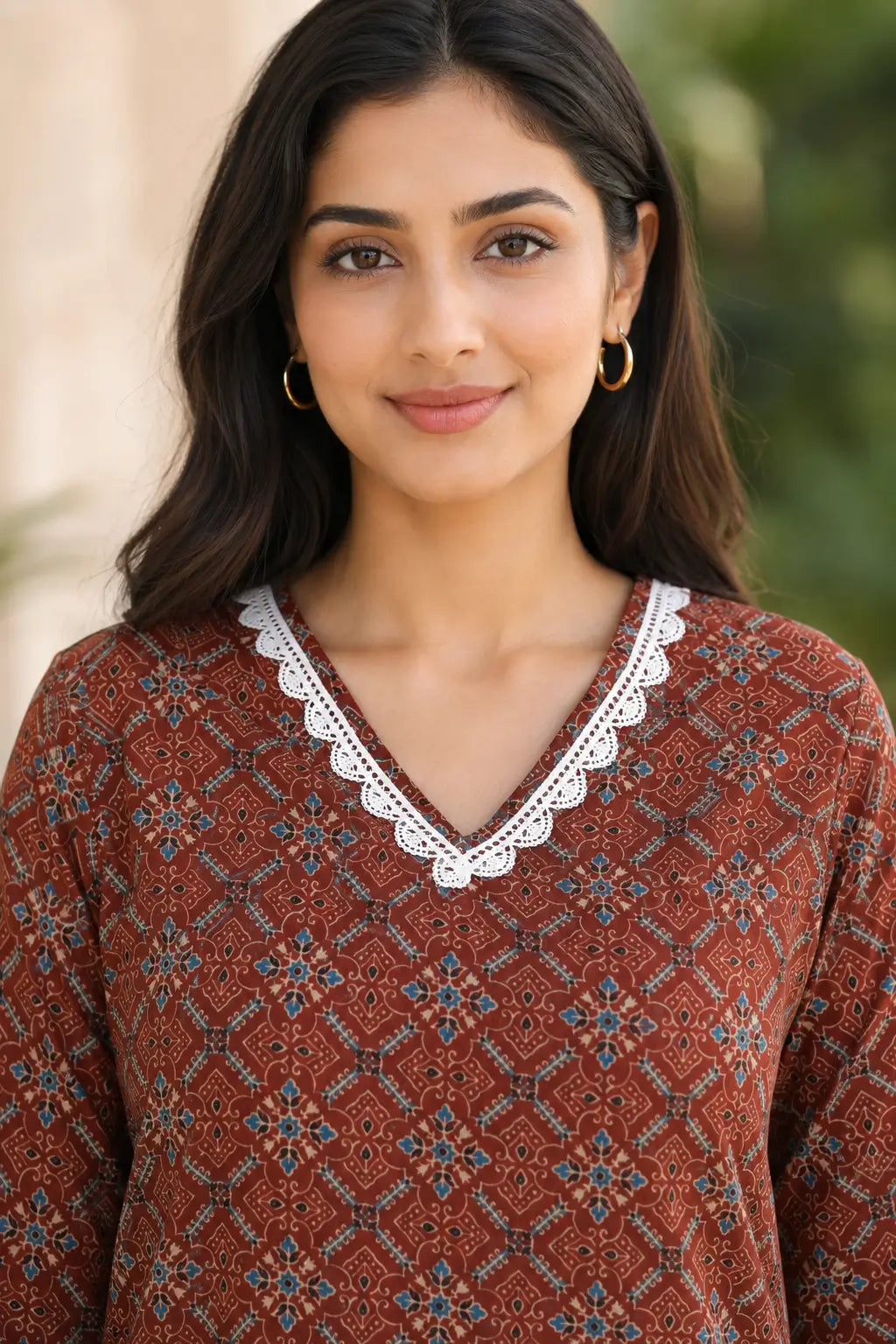 Close-up of Rabric rust brown cotton printed kurti with V-neck, white embroidered lace neck design and ethnic geometric floral print