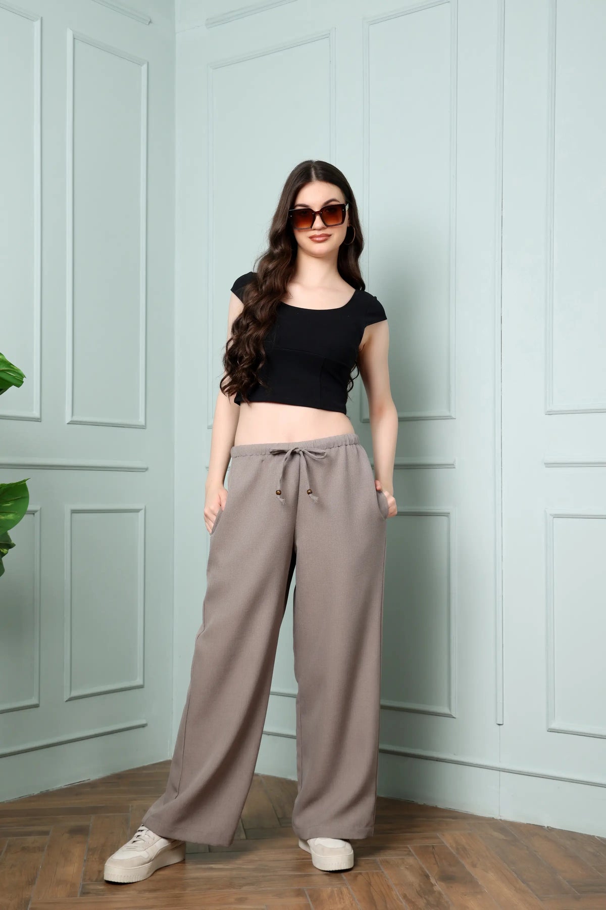 Standing front look of RABRIC taupe linen trousers for women with drawstring waist and wide legs