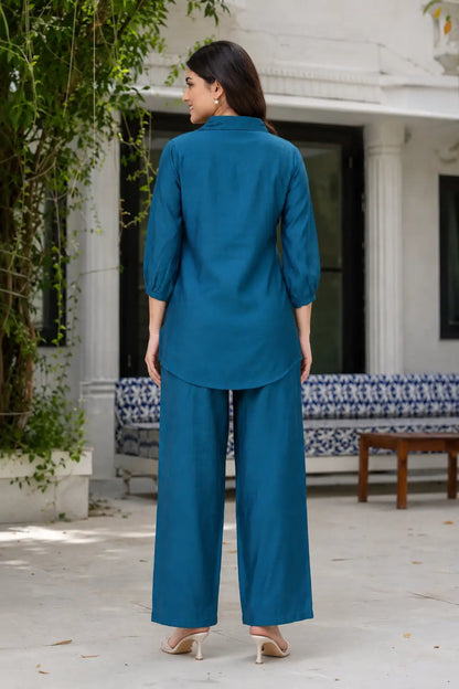Back view of Rabric teal blue Vertican silk co-ord set for women with collared short-length shirt, 3/4 sleeves, straight-fit pants and premium silk texture.
