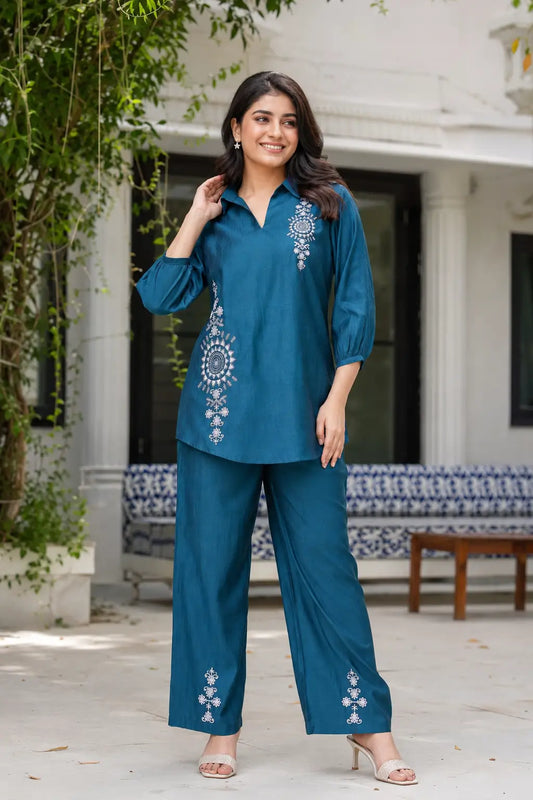 Rabric teal blue Vertican silk embroidered co-ord set for women featuring white floral ethnic embroidery, 3/4 sleeves, collared neck, straight pants and elegant front view.