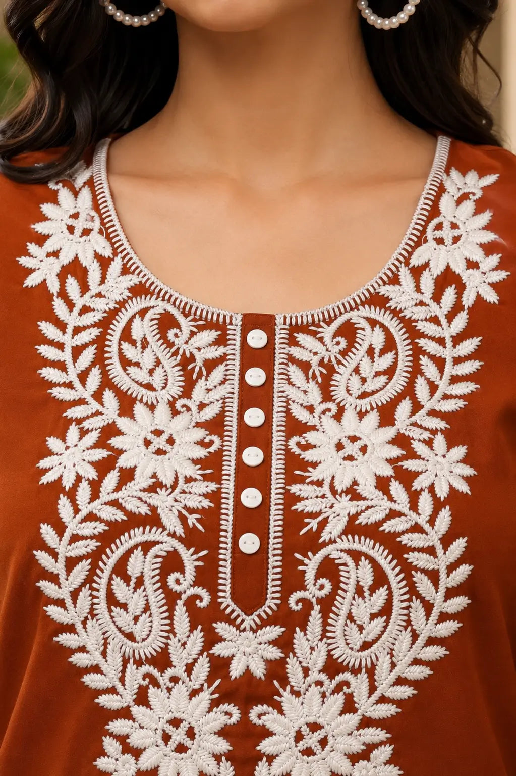 Close up neck design of rust cotton kurti with white floral embroidery and button detailing for women
