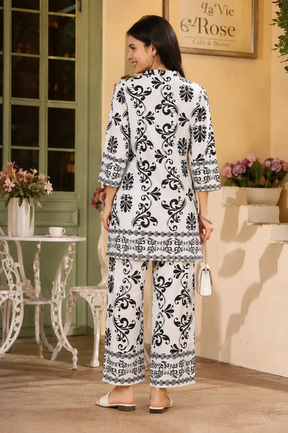 Back view of Rabric white Vertican Silk co-ord set for women with black floral damask print, short shirt style kurti and wide leg pant.