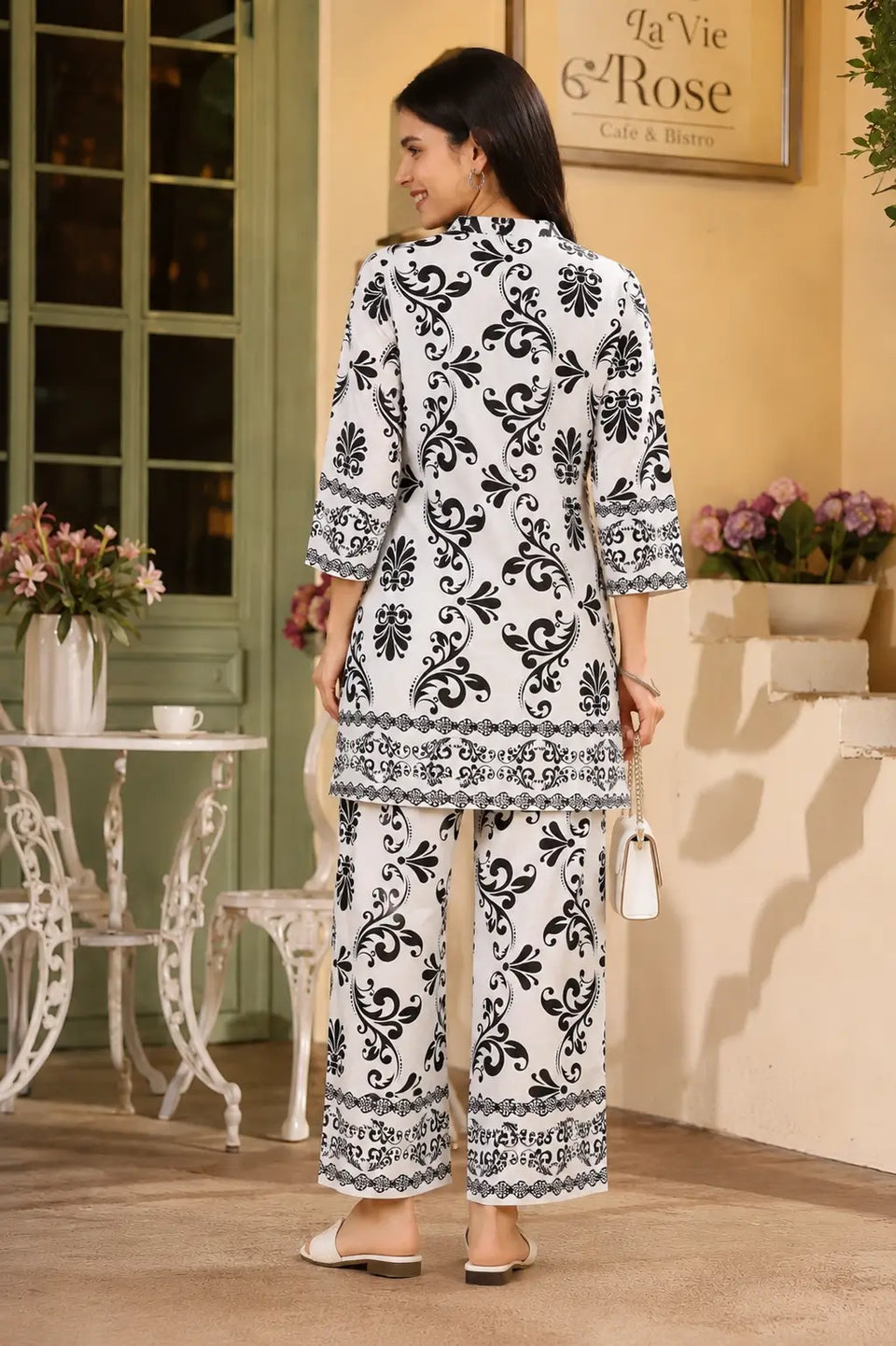 Back view of Rabric white Vertican Silk co-ord set for women with black floral damask print, short shirt style kurti and wide leg pant.