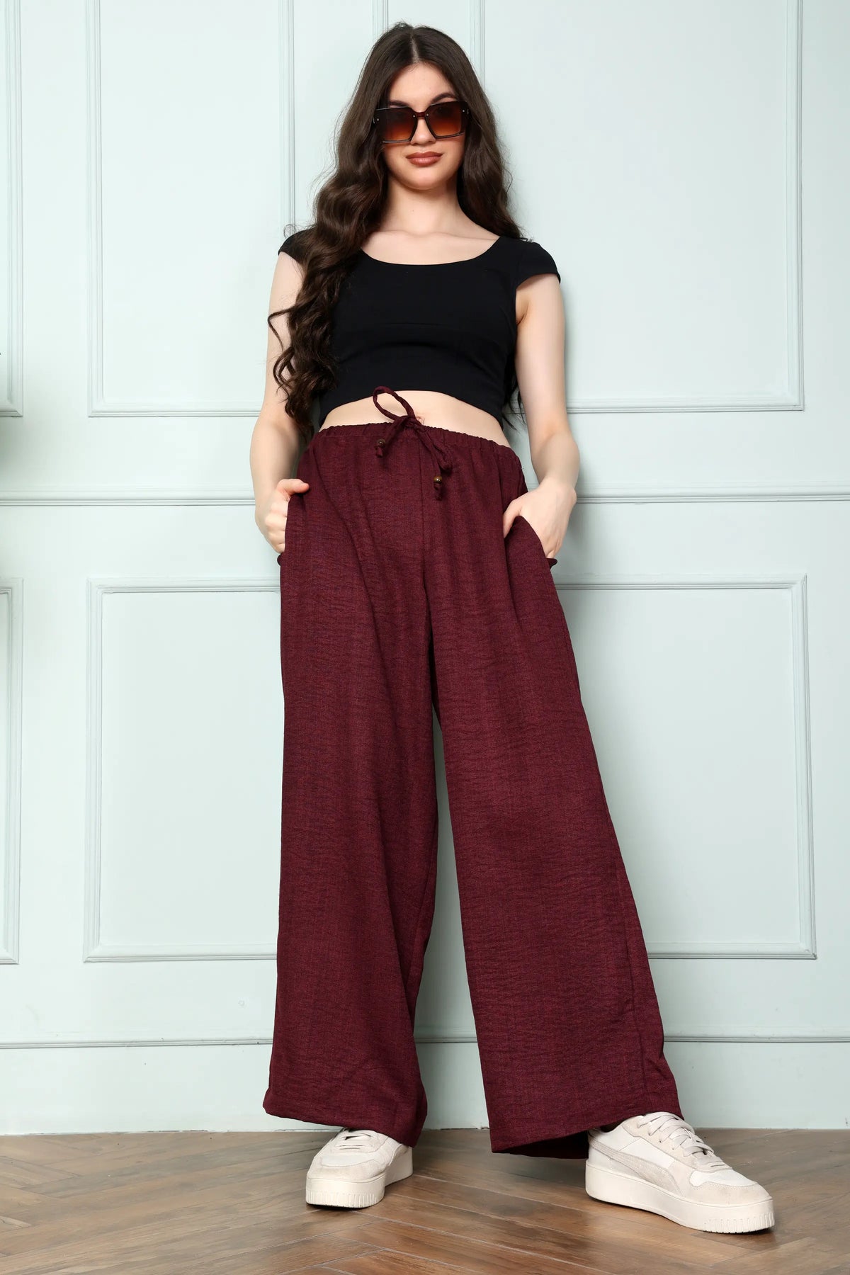 Woman wearing RABRIC wine linen wide leg trousers in standing pose showing full-length relaxed fit