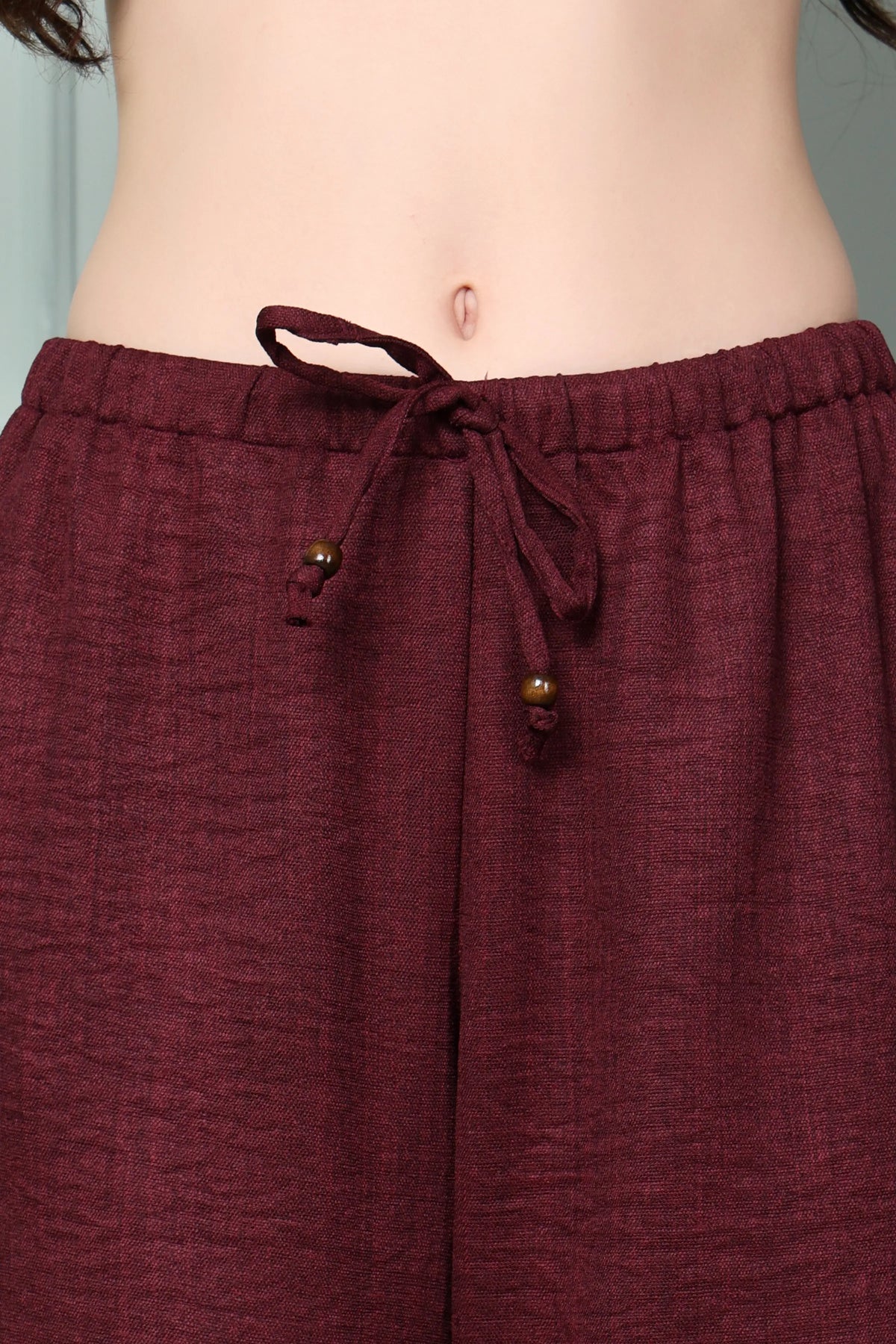 Close-up of RABRIC wine linen trousers for women with drawstring wooden rings and side pocket