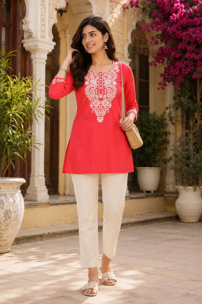 Woman wearing coral pink cotton embroidered short kurti with casual ethnic styling and straight pants