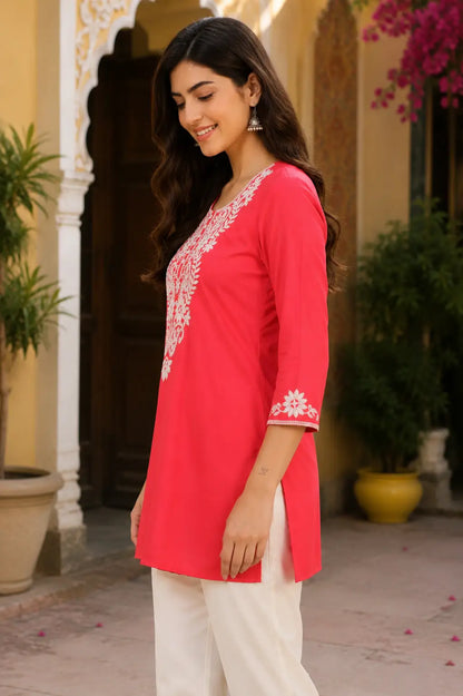 Side angle view of women coral pink cotton embroidered short top by Rabric with stylish straight silhouette