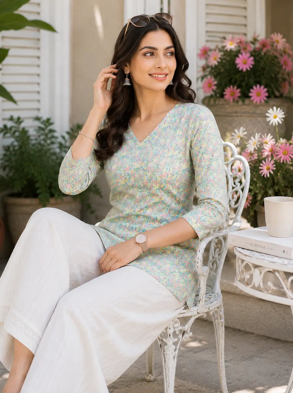 Lifestyle sitting pose of model wearing Rabric floral cotton short top with casual accessories and white palazzo pants
